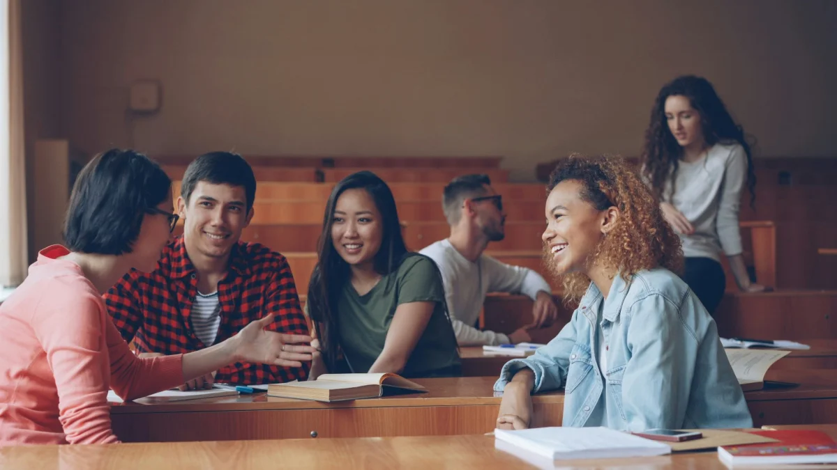 Students talking at wooden desks in a classroom