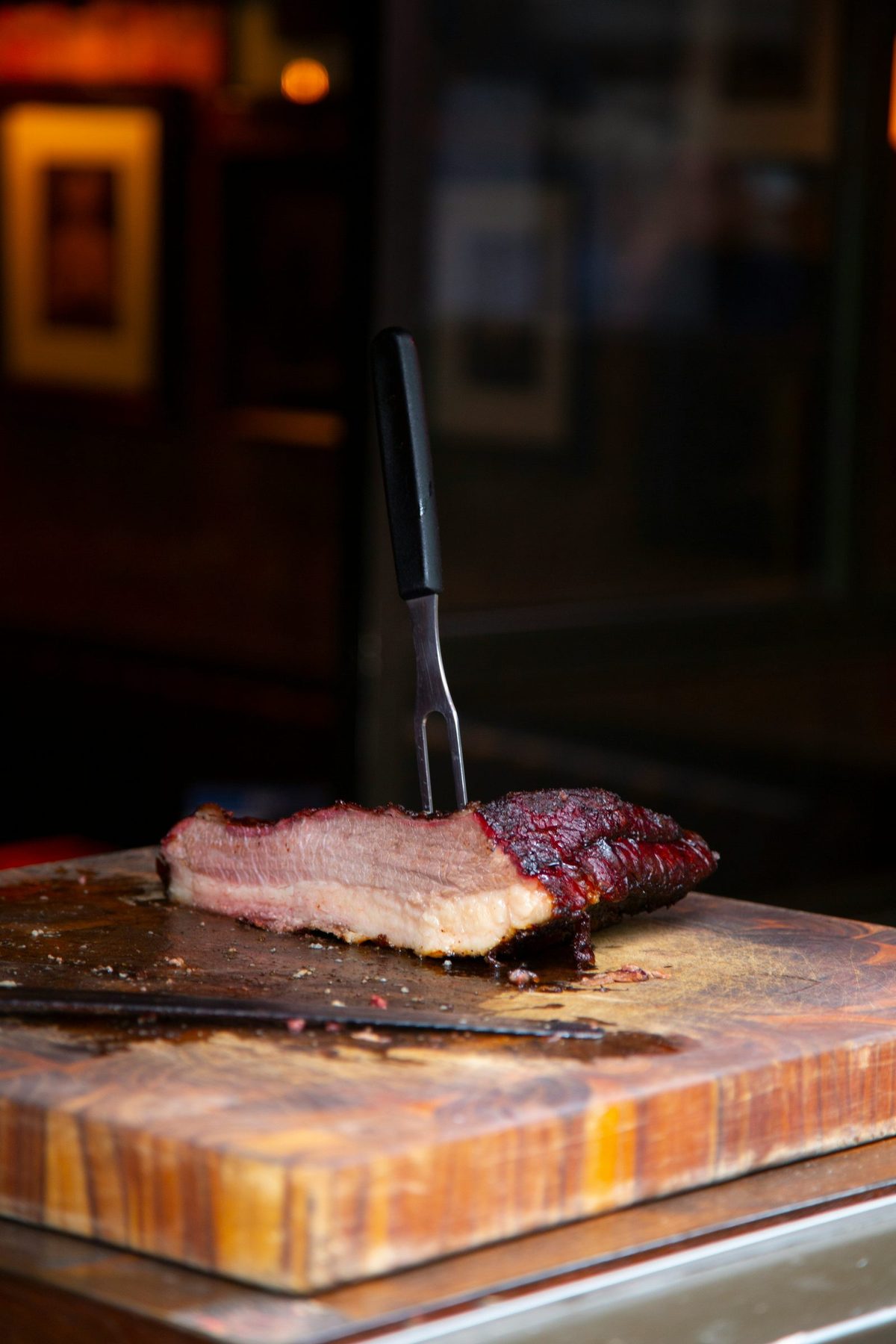 A slab of smoked Texas brisket resting on a wooden board with a carving fork