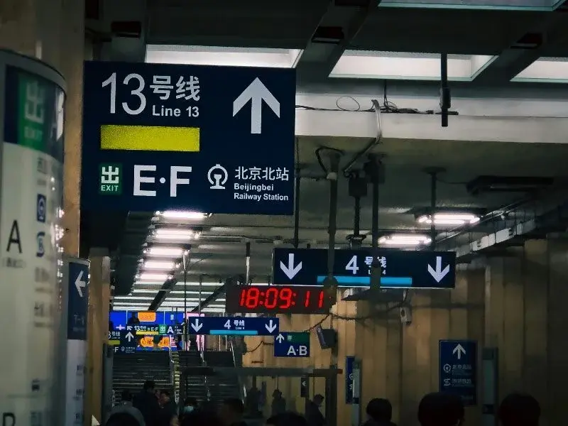 An overhead directional sign in a Beijing subway station pointing toward Line 13 and Beijingbei Railway Station