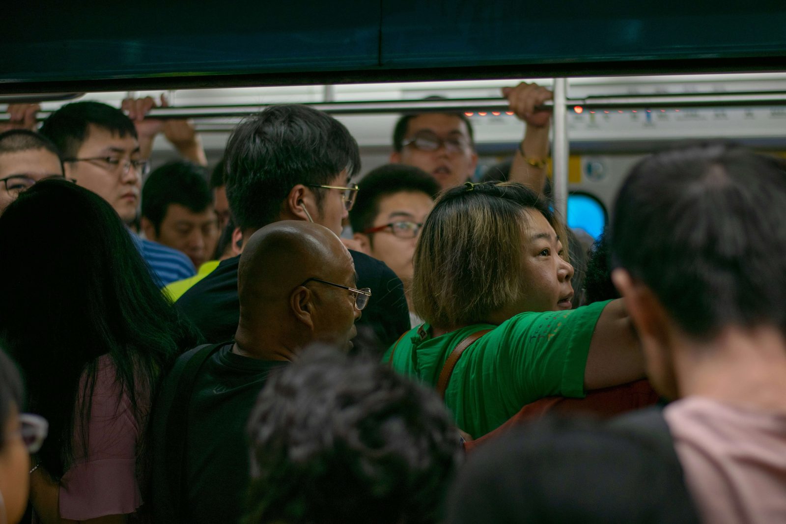 A packed Beijing subway car at rush hour, passengers pressed shoulder to shoulder holding the overhead rail