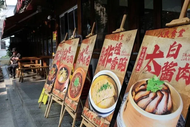 A row of illustrated menu boards outside a Chengdu restaurant advertising braised pork, chicken soup, and other home-style dishes