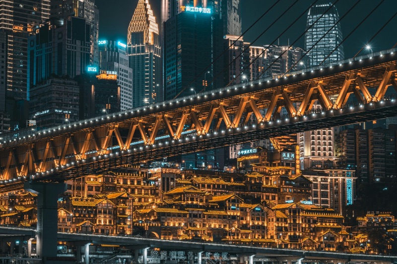 Hongyadong stilt-house buildings lit up at night in Chongqing, seen from a bridge over the river