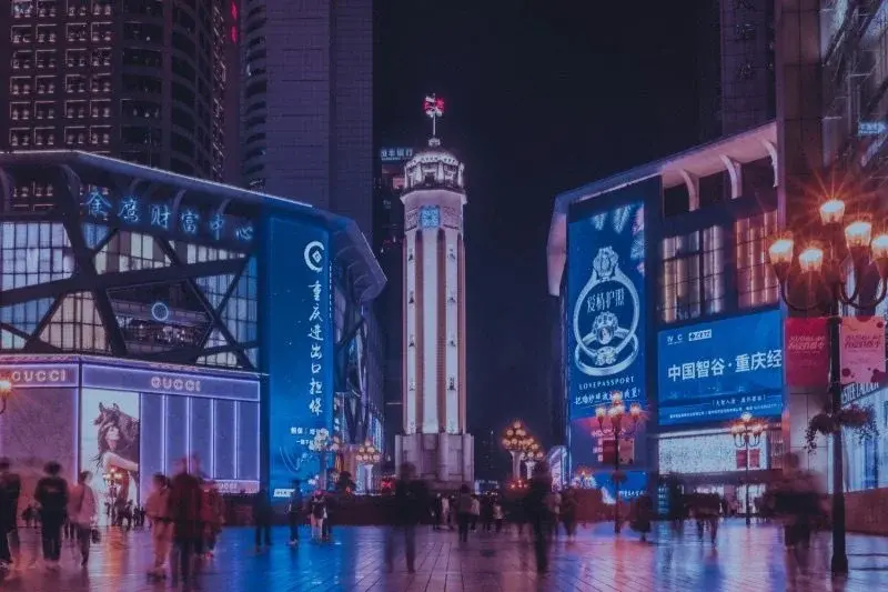 Jiefangbei Liberation Monument clock tower lit up at night, surrounded by shopping district crowds