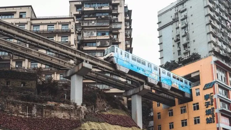 A light rail train emerging from between the sixth and eighth floors of a residential building at Liziba station, Chongqing