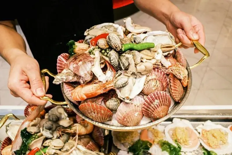 A large tray heaped with steamed scallops, oysters, clams, prawns and squid
