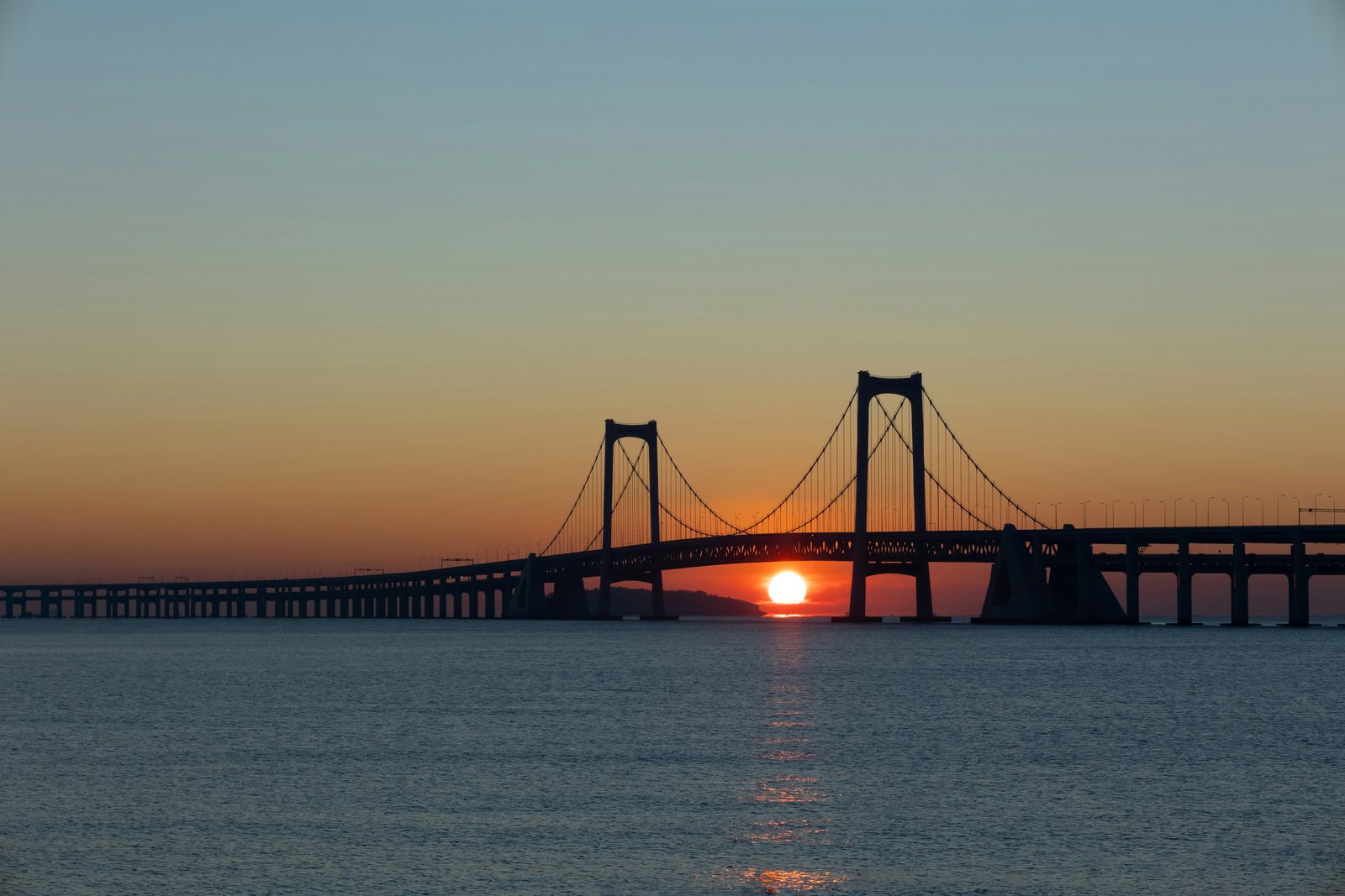 The Xinghai Bay cross-sea bridge at sunset over calm water