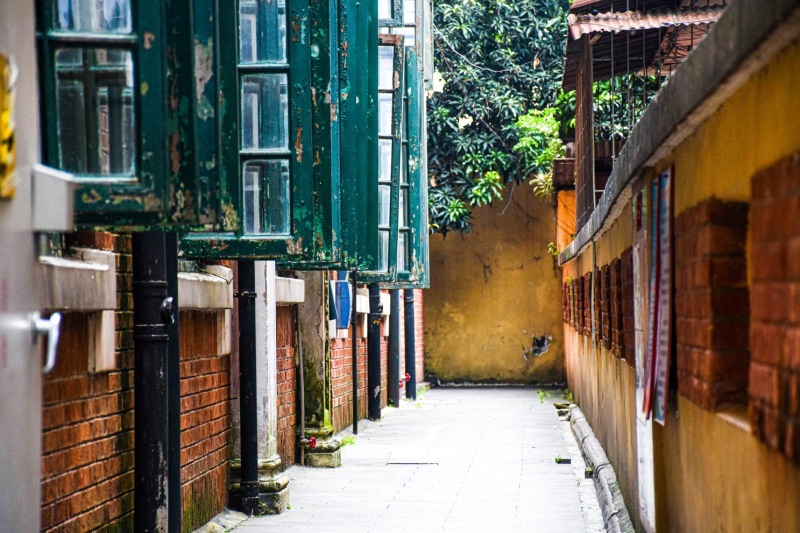 A quiet alley on Shamian Island, Guangzhou, lined with weathered colonial-era shutters and brick walls