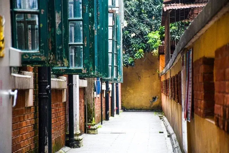 A quiet alley on Shamian Island, Guangzhou, lined with weathered colonial-era shutters and brick walls