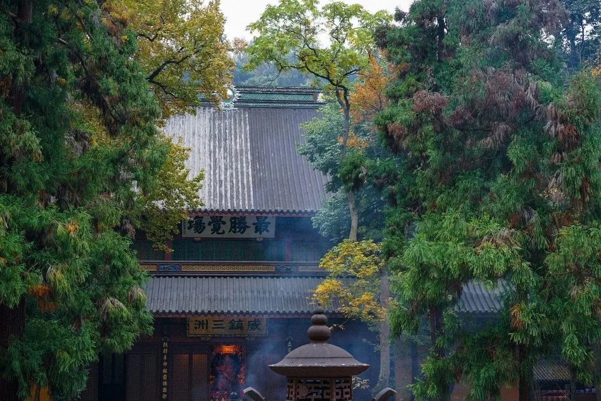 A temple hall glimpsed through trees at Lingyin Temple near Hangzhou, incense smoke rising from a burner