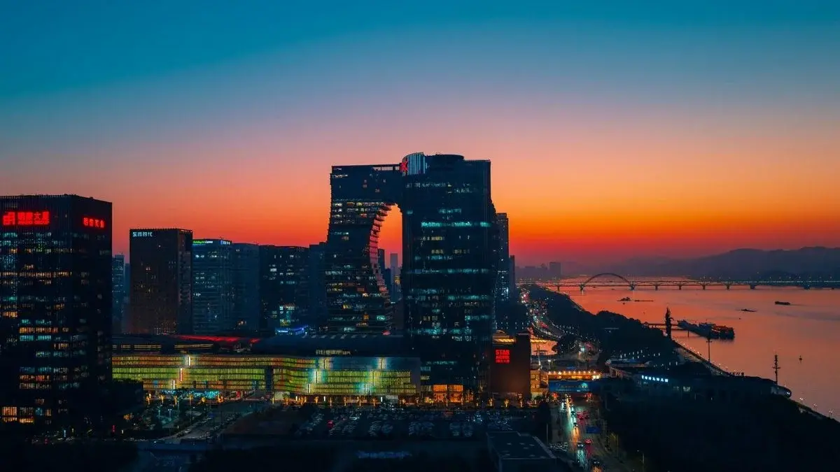 Modern office towers along the Qiantang River in Hangzhou at sunset, part of the city's platform-economy business district