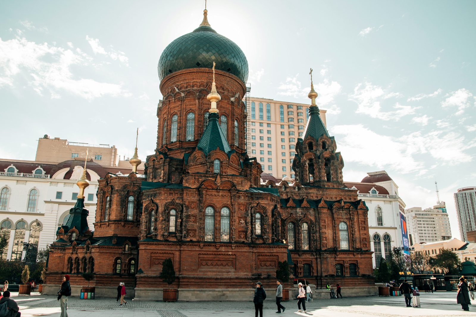 Saint Sophia Cathedral, a Russian Orthodox church with a green onion dome, with a modern high-rise directly behind it