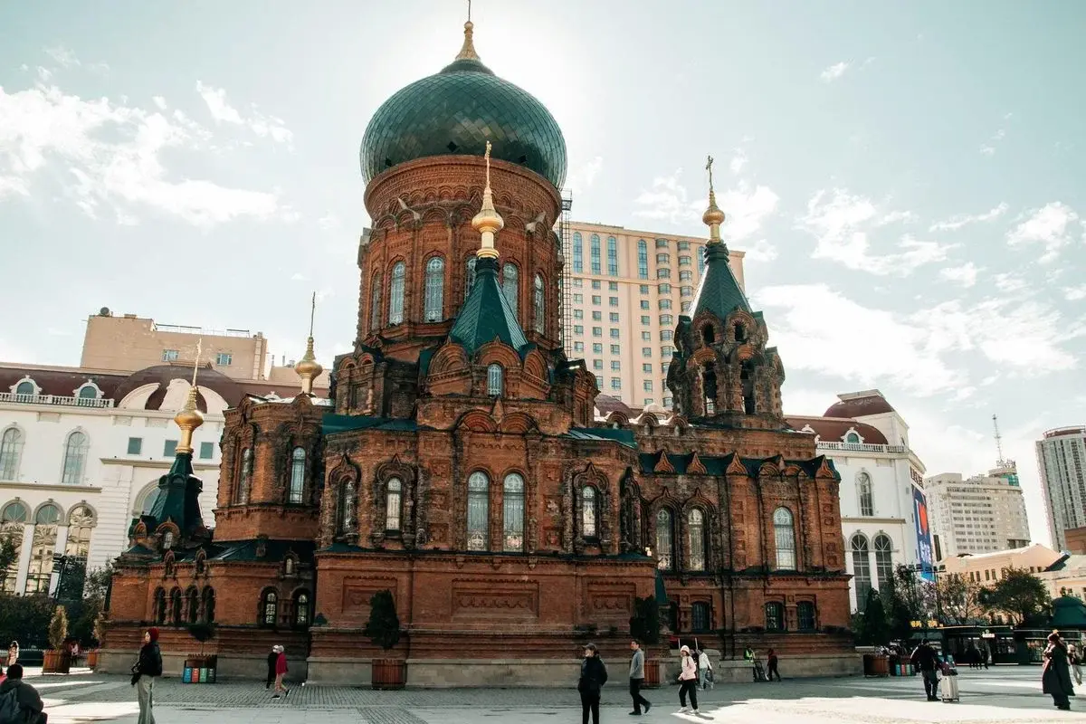Saint Sophia Cathedral, a Russian Orthodox church with a green onion dome, with a modern high-rise directly behind it