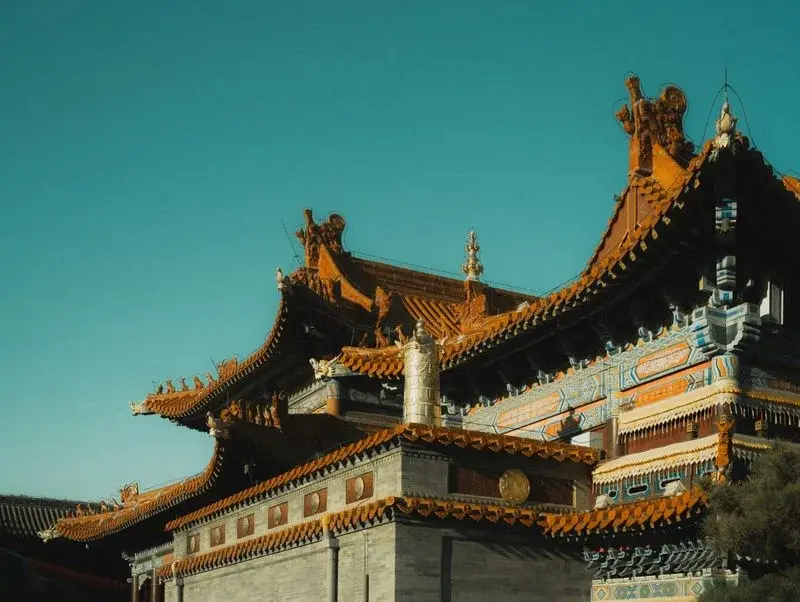 Ornate orange and teal roof detail of a Tibetan-Buddhist-style temple in Hohhot against a clear sky
