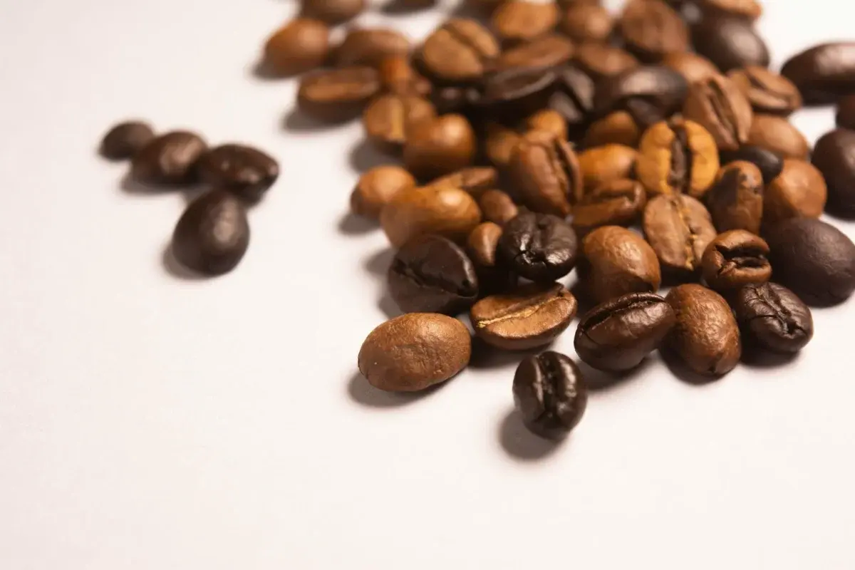 Roasted coffee beans of varying roast levels scattered across a white surface