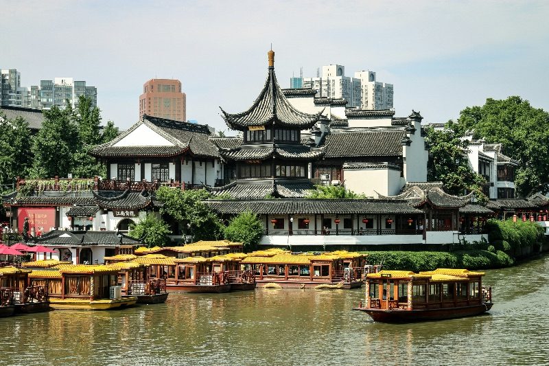 Yellow-canopied tour boats moored along the Qinhuai River in front of the pagoda-roofed Confucius Temple complex in Nanjing