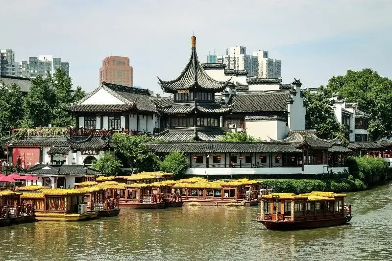 Yellow-canopied tour boats moored along the Qinhuai River in front of the pagoda-roofed Confucius Temple complex in Nanjing
