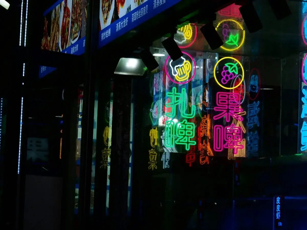Neon signs in Chinese advertising draft beer and fruit beer outside a Qingdao restaurant at night