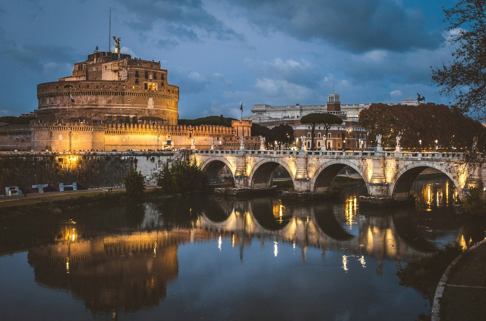 Castel Sant'Angelo and the statue-lined Ponte Sant'Angelo reflected in the Tiber at dusk