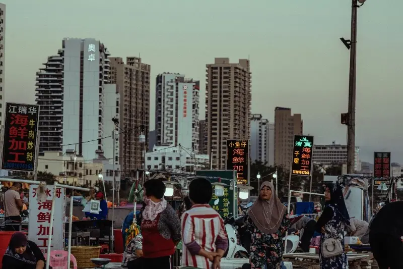 The vibrant atmosphere of a local night seafood market in Sanya, with neon signs and customers