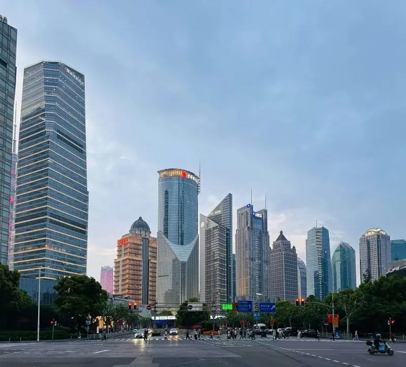 Lujiazui office towers above Century Avenue in Pudong at dusk, pedestrians crossing a wide boulevard