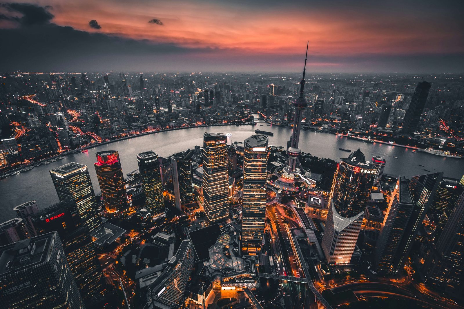 Aerial view of Shanghai at dusk, the Oriental Pearl Tower and Lujiazui towers above a bend in the Huangpu River