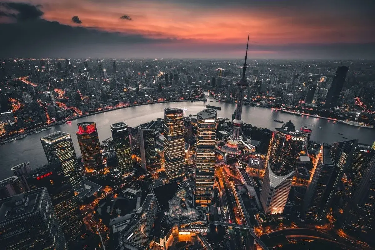 Aerial view of Shanghai at dusk, the Oriental Pearl Tower and Lujiazui towers above a bend in the Huangpu River