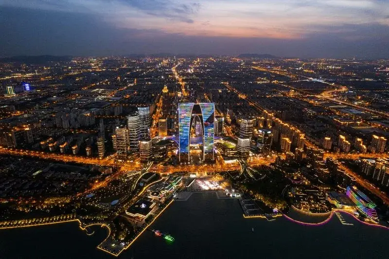 High-rise office and residential towers in the Suzhou Industrial Park CBD at night, lit up in blue and purple