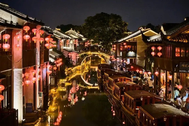 Shantang Street at night, red lanterns lining the canal with tour boats moored along the water