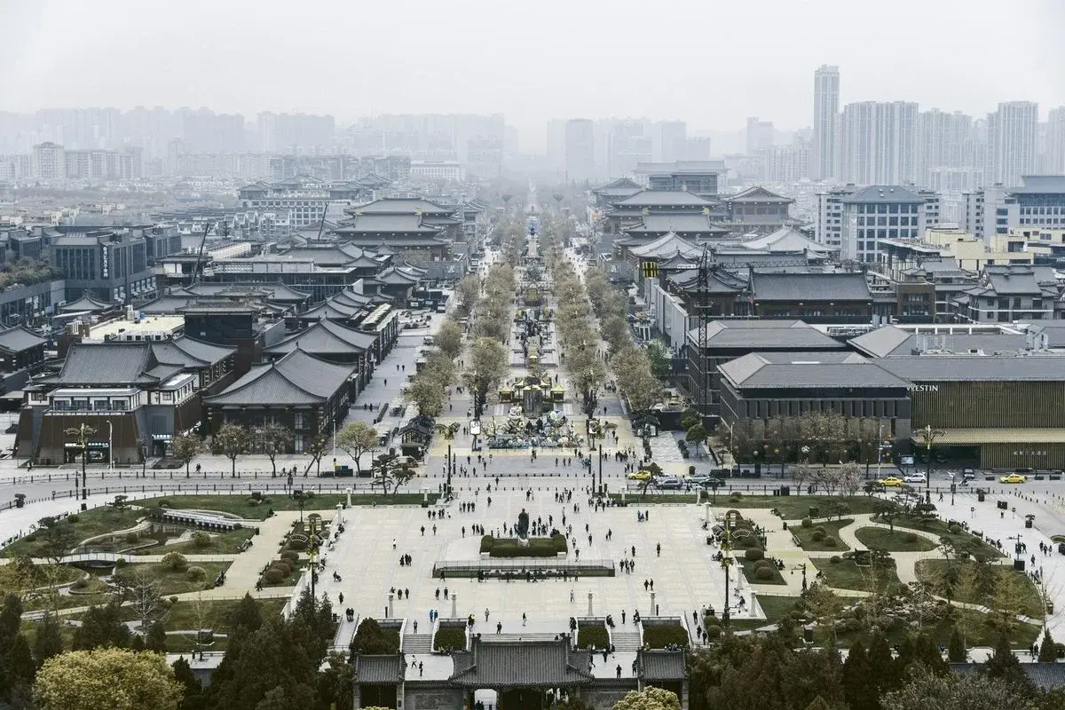 Aerial view down Xi'an's grand Tang-style axis, traditional roofs in the foreground and modern high-rises fading into haze