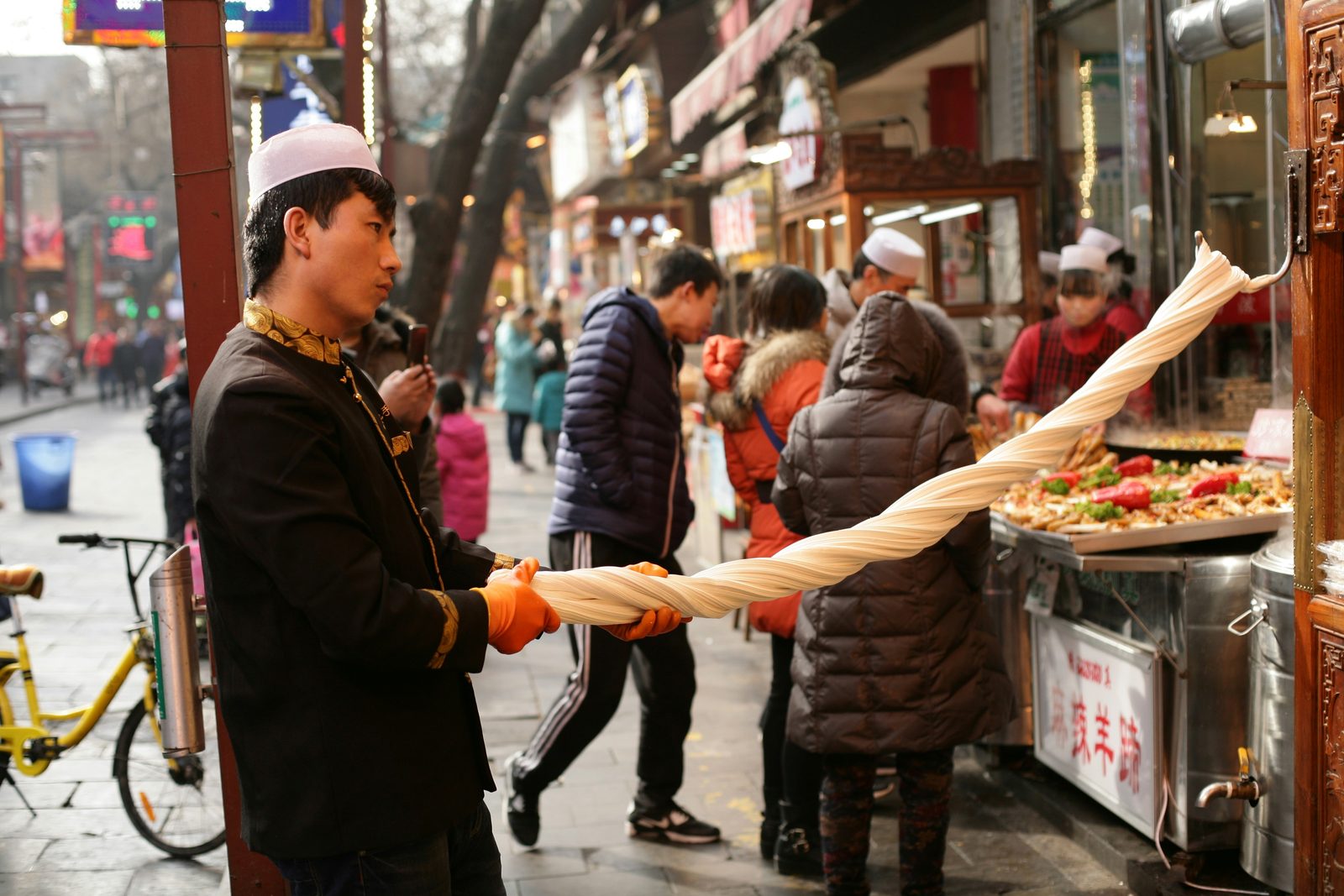 Neon signs crowd above a dense evening crowd in Xi'an's Muslim Quarter food street