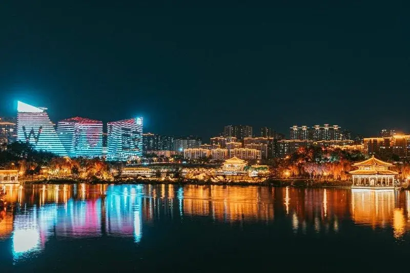 Xi'an at night: illuminated Tang-style pavilions along a lake, LED-lit towers rising behind them