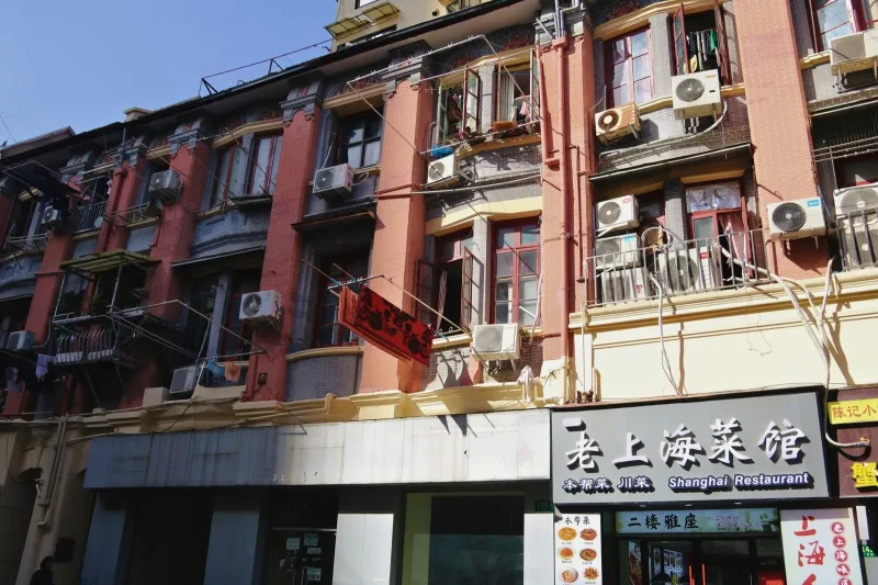An older Shanghai street block of walk-up apartments with air-conditioning units and laundry drying over the street