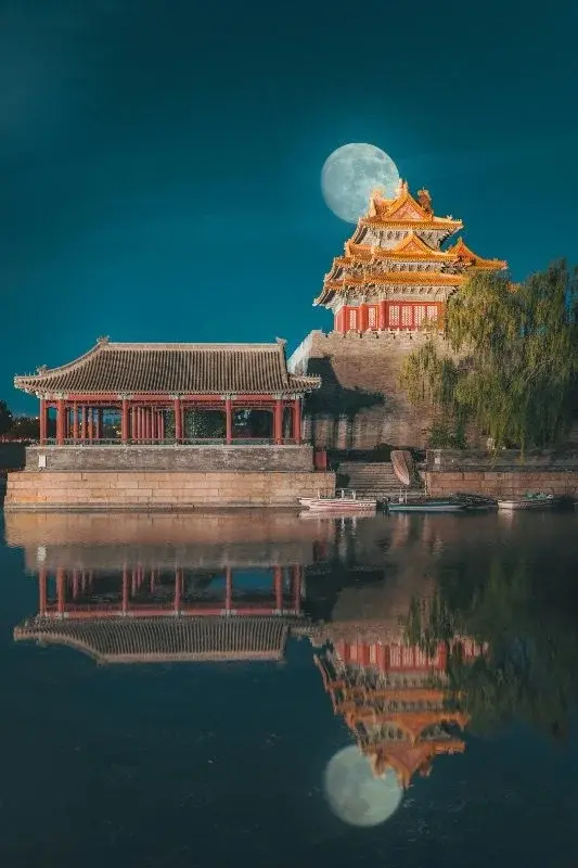 A Forbidden City corner watchtower at dusk with the moon rising behind it, reflected in the moat