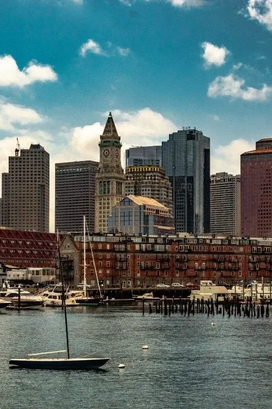 The Boston Custom House Tower rising above the Financial District, seen across Boston Harbor with a sailboat in the foreground