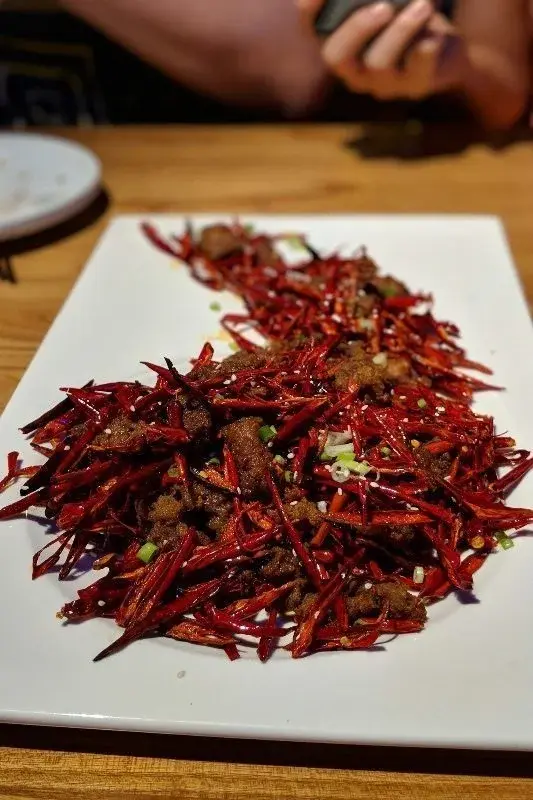 A Sichuan dry-fried chili dish, dark chunks of meat buried under a mound of dried red chilies