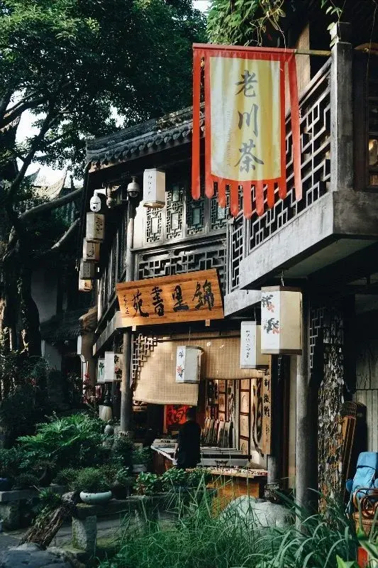 A traditional Chengdu teahouse storefront in a historic lane, with hanging lanterns and a red banner reading 'Old Sichuan Tea'