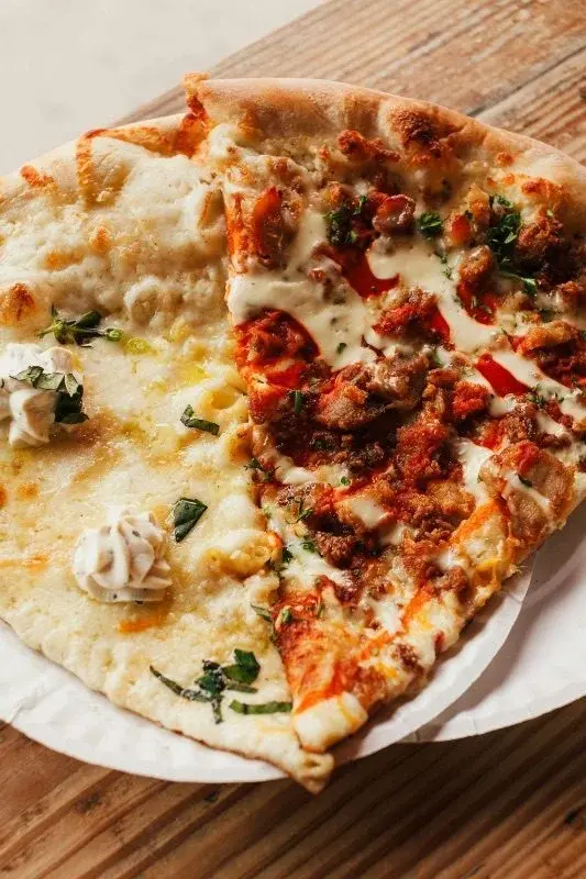 A slice of Chicago deep-dish pizza with a thick, sauce-and-cheese-loaded crust on a paper plate