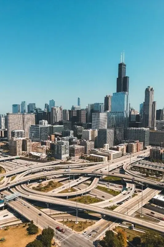 An aerial view of Chicago's expressway interchange with the downtown skyline and Willis Tower in the background