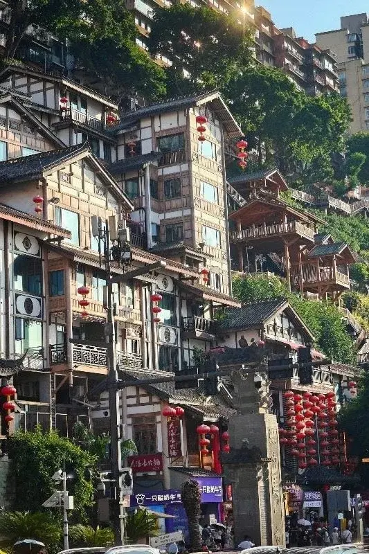 A restored old-town district in Chongqing built up a hillside, with red lanterns hanging between traditional wood-frame buildings and modern high-rises visible above