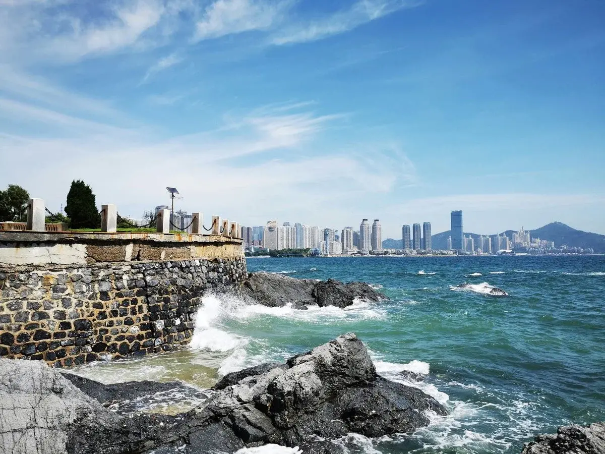 Dalian's rocky coastline with the city skyline across the bay