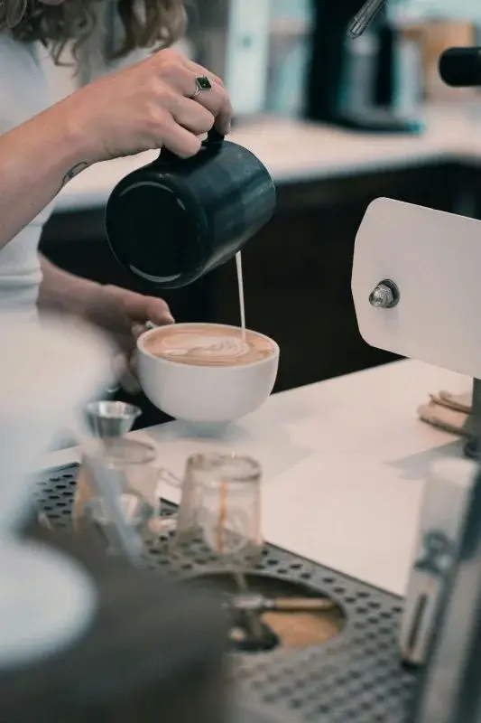 A barista pouring latte art into a cup at a Denver coffee bar
