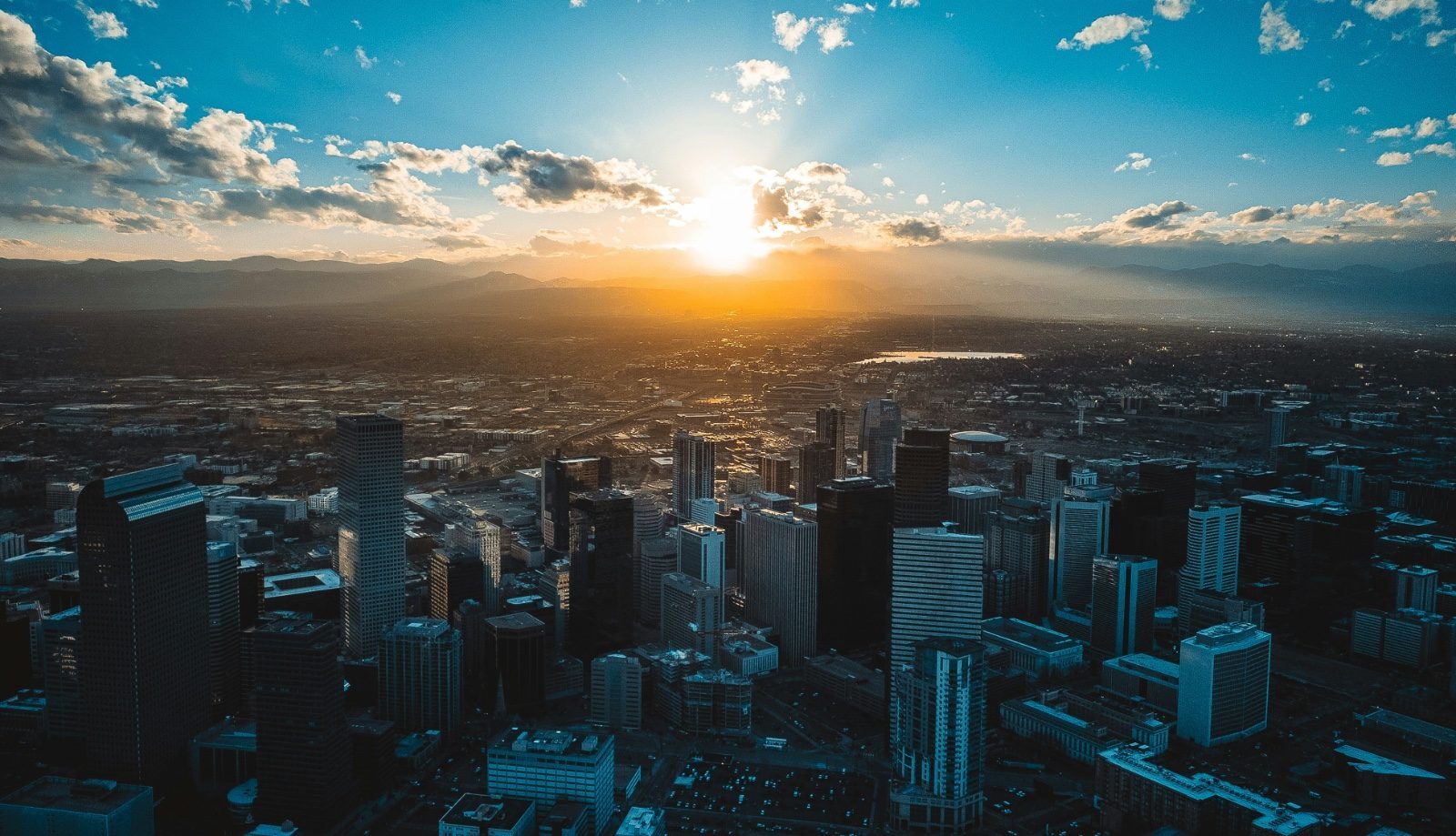 Aerial view of downtown Denver at sunrise with the Rocky Mountains behind it