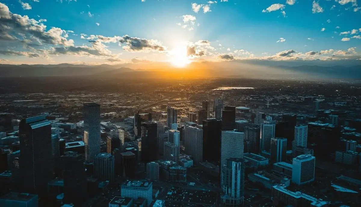 Aerial view of downtown Denver at sunrise with the Rocky Mountains behind it