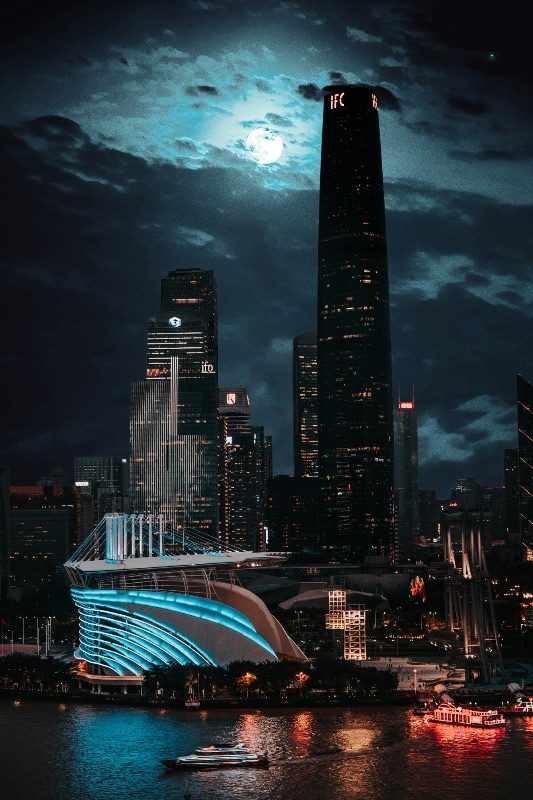 Guangzhou's Zhujiang New Town skyline at night, including the IFC tower and the Opera House, under a full moon