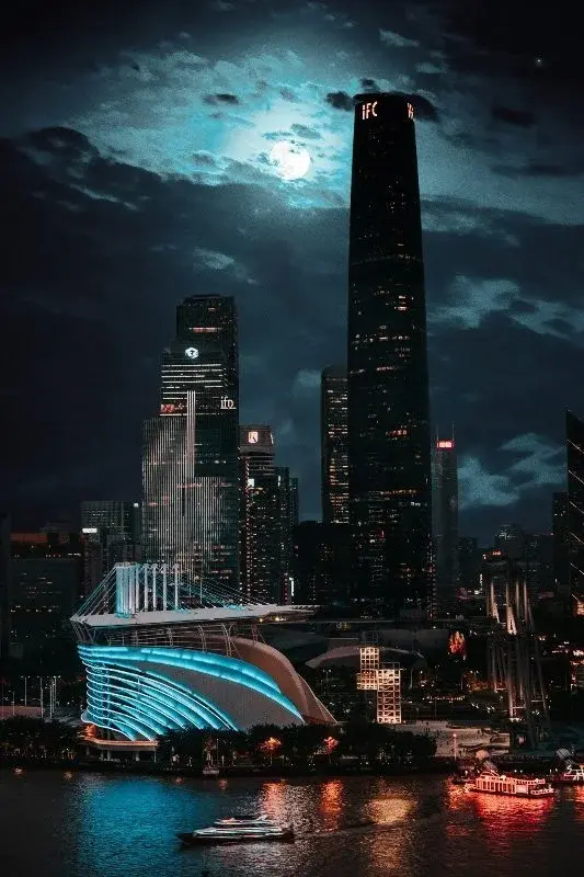 Guangzhou's Zhujiang New Town skyline at night, including the IFC tower and the Opera House, under a full moon