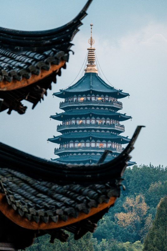 Leifeng Pagoda at West Lake glimpsed through the upturned eaves of a temple roof in Hangzhou