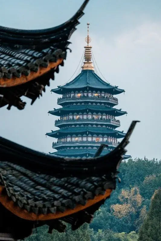 Leifeng Pagoda at West Lake glimpsed through the upturned eaves of a temple roof in Hangzhou