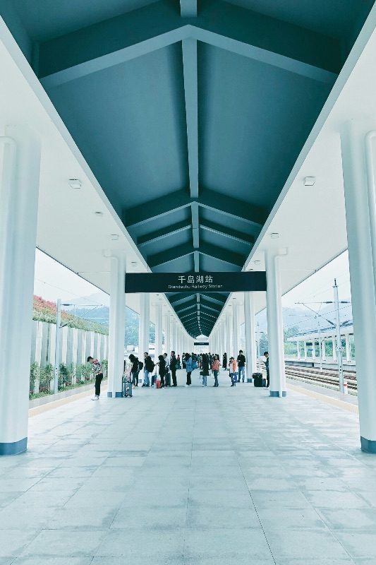 Passengers waiting on the platform at Qiandaohu Railway Station, a bright covered high-speed rail station near Thousand Island Lake