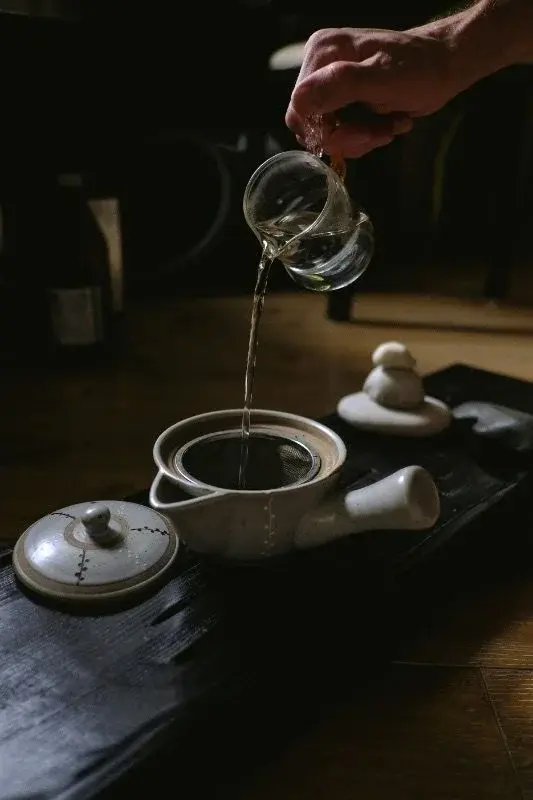 Gongfu-style tea being poured from a glass fairness cup into a strainer near Hangzhou