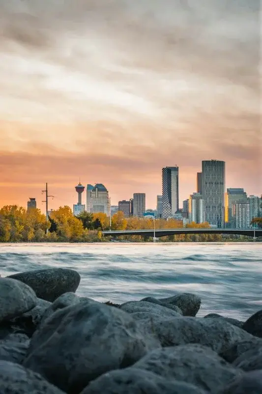 Calgary's downtown skyline at sunset seen across the Bow River, the Calgary Tower visible among the office towers